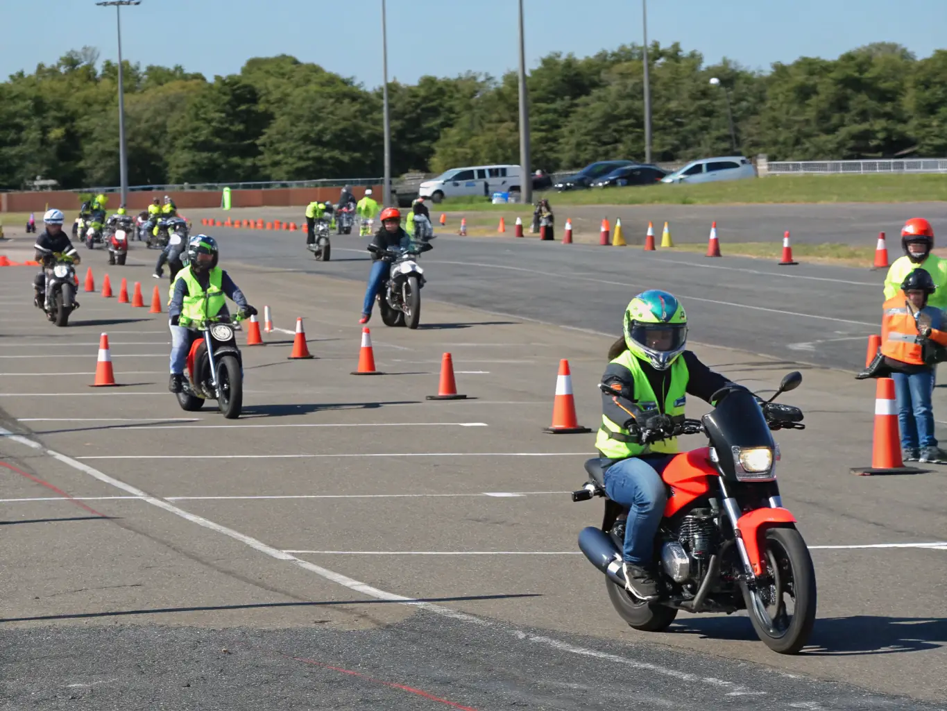 A group of young motocross riders participating in a training session on a dirt track, with instructors providing guidance and feedback.